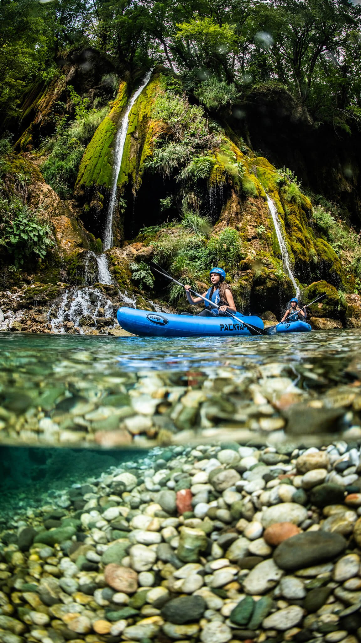 Two women paddling bright inflatable packrafts through the green waters of the Tara River Canyon in Montenegro.
