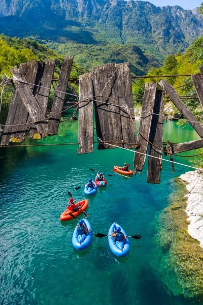 Group of adventure travelers paddling inflatable packrafts down the turquoise waters of Tara River Canyon in Montenegro